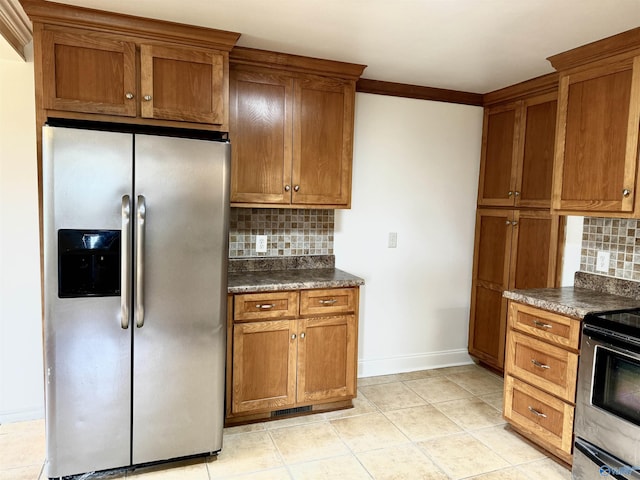 kitchen with appliances with stainless steel finishes, dark countertops, brown cabinets, and backsplash