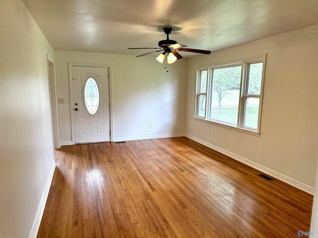 foyer entrance with wood finished floors, visible vents, a ceiling fan, and baseboards