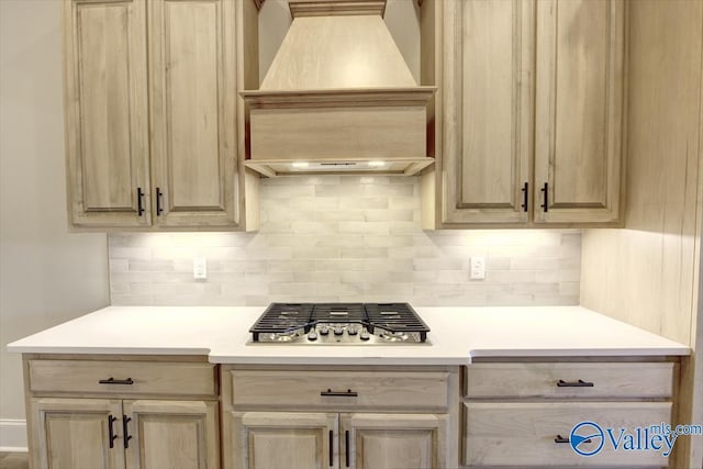 kitchen featuring backsplash, stainless steel gas stovetop, light brown cabinets, and custom exhaust hood