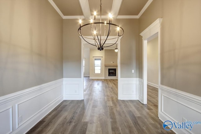 unfurnished dining area featuring hardwood / wood-style flooring, crown molding, and a chandelier