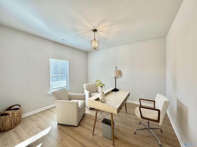 living area with light wood finished floors, baseboards, a desk, and a chandelier