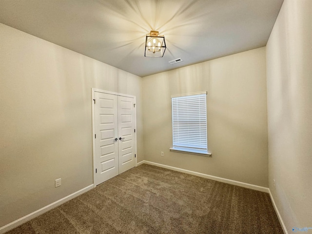 carpeted spare room featuring baseboards and a chandelier