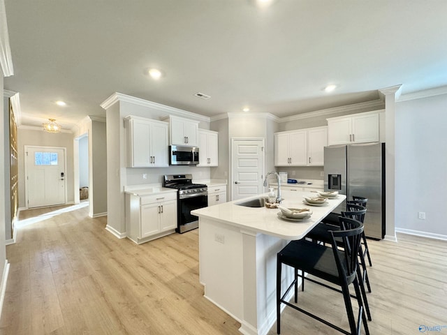 kitchen featuring stainless steel appliances, a sink, ornamental molding, baseboards, and white cabinetry
