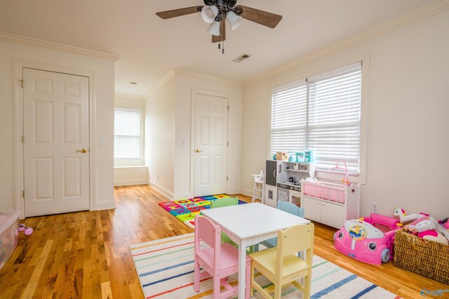 playroom with ornamental molding, ceiling fan, and light hardwood / wood-style floors