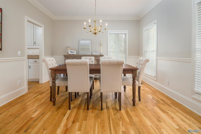 dining area featuring crown molding, a notable chandelier, and light hardwood / wood-style flooring