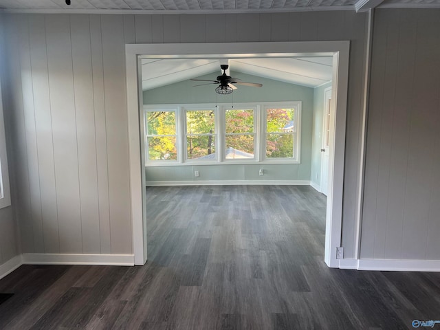 interior space featuring dark wood-type flooring, ceiling fan, wood walls, and lofted ceiling