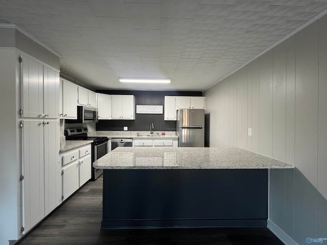 kitchen with dark wood-type flooring, sink, white cabinets, appliances with stainless steel finishes, and light stone counters