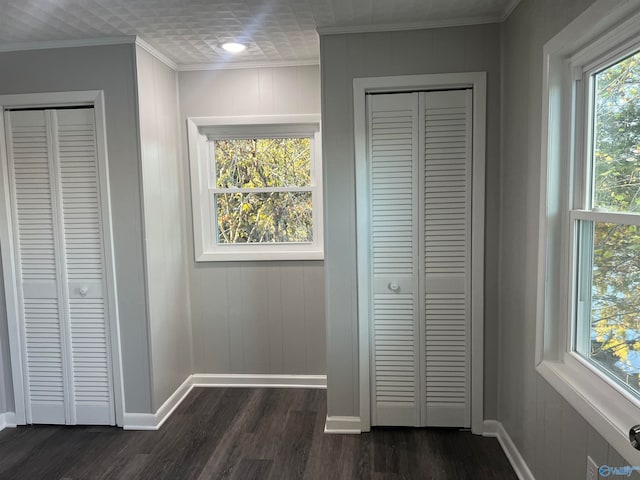 unfurnished bedroom with multiple closets, crown molding, dark hardwood / wood-style floors, and wood walls