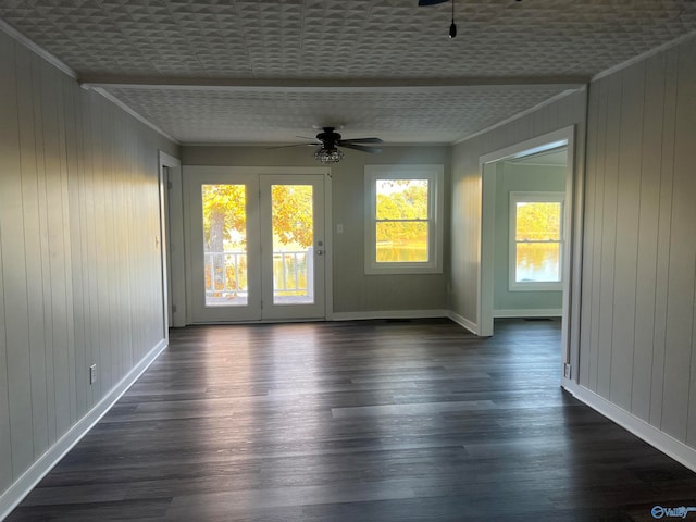 unfurnished room featuring ornamental molding, ceiling fan, wooden walls, and dark hardwood / wood-style flooring