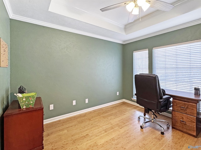 office featuring light hardwood / wood-style floors, crown molding, a raised ceiling, and ceiling fan