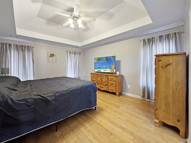 bedroom with ceiling fan, light hardwood / wood-style floors, and a raised ceiling