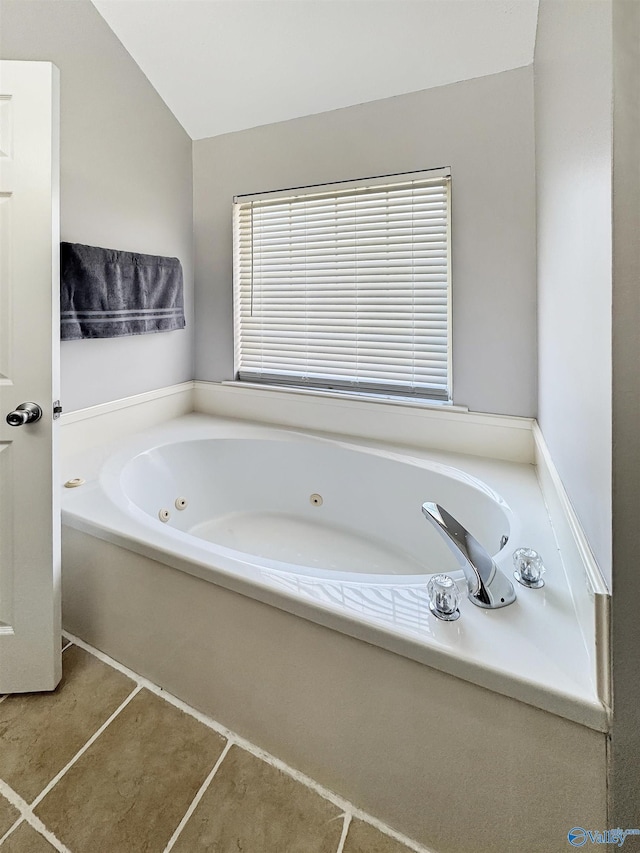 bathroom with vaulted ceiling, tile patterned floors, and a tub to relax in