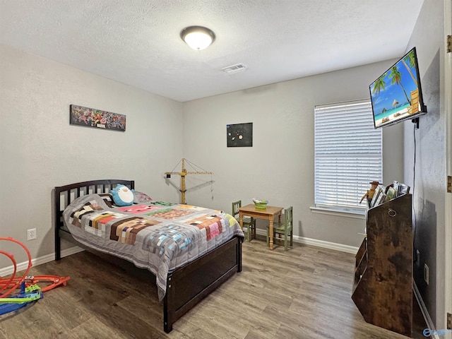 bedroom with light wood-type flooring and a textured ceiling