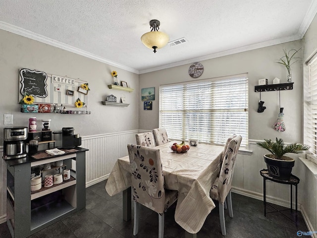 dining room with a textured ceiling, dark tile patterned floors, and crown molding