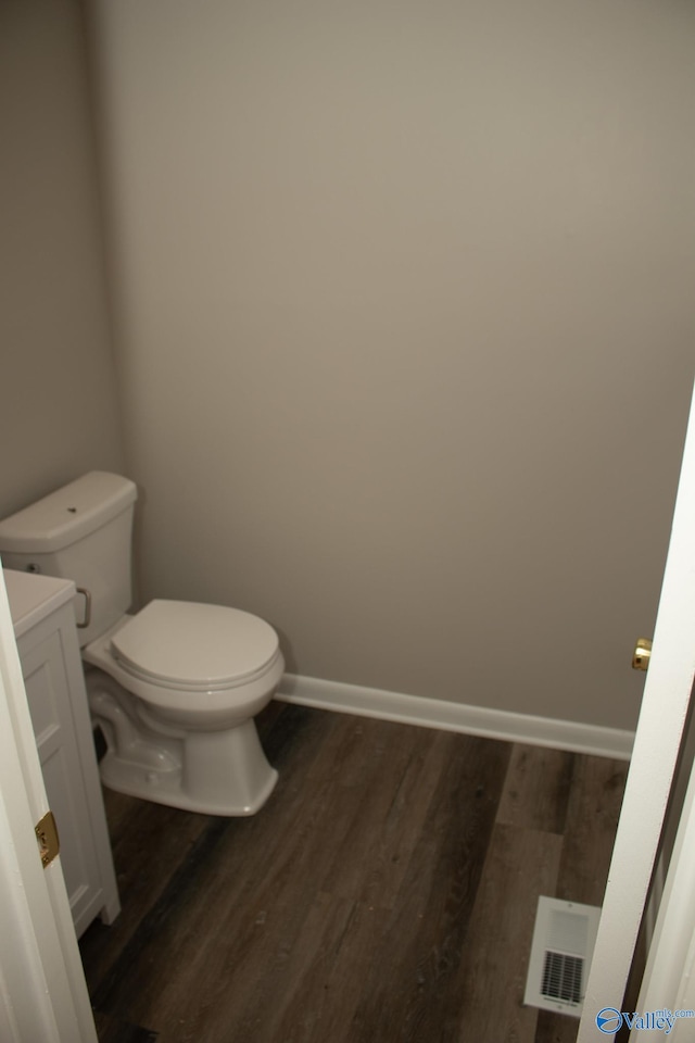 bathroom with wood-type flooring, vanity, and toilet