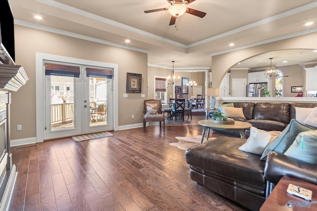 living area featuring arched walkways, french doors, crown molding, dark wood-type flooring, and ceiling fan with notable chandelier