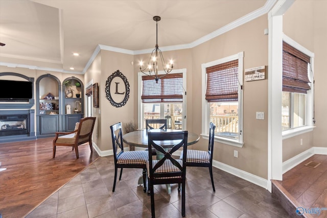 dining room with a wealth of natural light, dark wood finished floors, a glass covered fireplace, and a notable chandelier