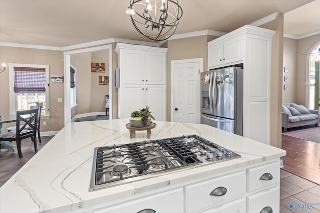 kitchen with white cabinets, appliances with stainless steel finishes, a chandelier, and crown molding