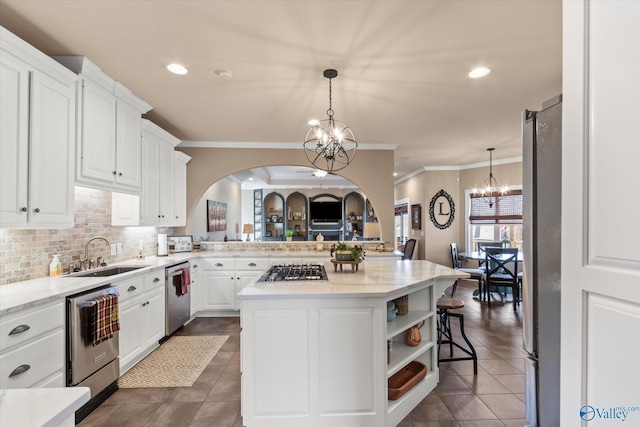 kitchen with tasteful backsplash, appliances with stainless steel finishes, an inviting chandelier, white cabinetry, and a sink