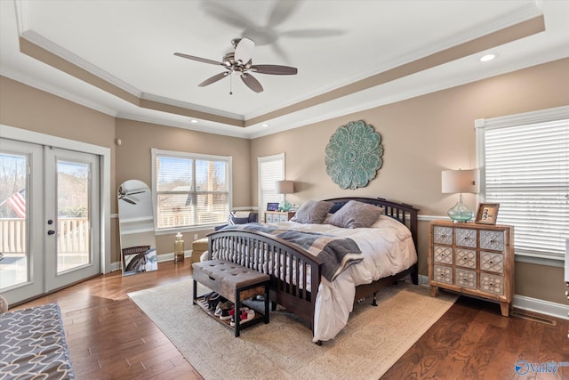 bedroom with access to exterior, baseboards, a tray ceiling, and wood finished floors