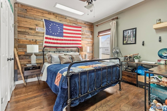 bedroom with ceiling fan, wood walls, and wood finished floors