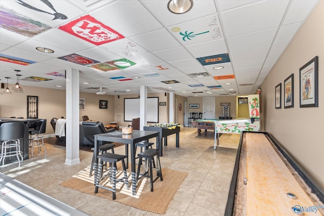 interior space with visible vents, light tile patterned flooring, a bar, a drop ceiling, and baseboards