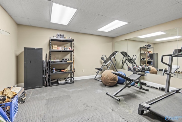 workout area featuring baseboards and a drop ceiling