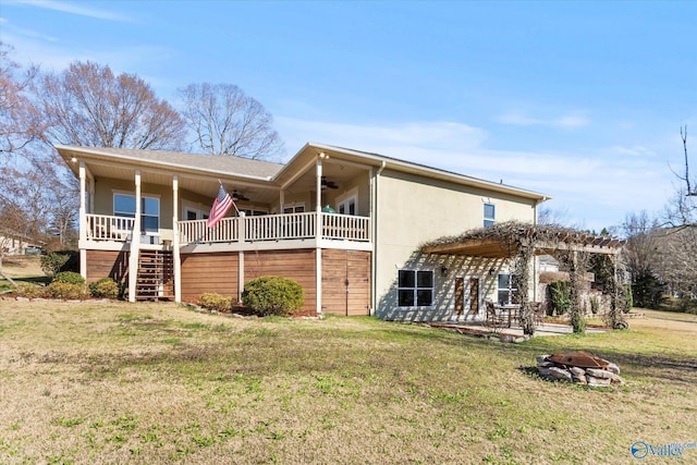 back of house featuring a ceiling fan, a fire pit, a lawn, and stairway