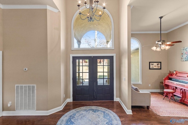 entrance foyer featuring a notable chandelier, wood finished floors, visible vents, baseboards, and crown molding