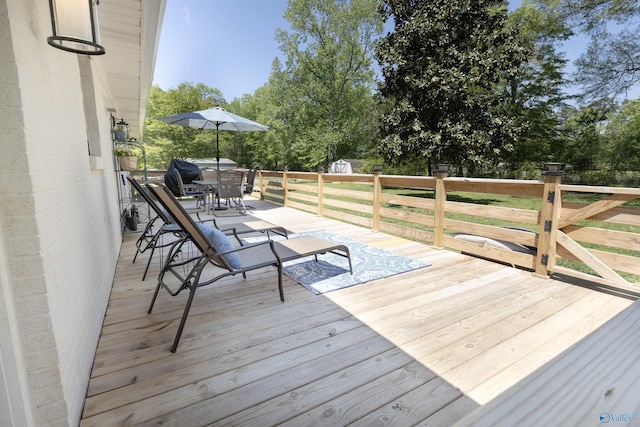 wooden terrace with an outbuilding, outdoor dining space, and a storage shed