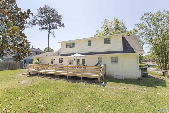 rear view of property featuring a lawn, a deck, a shingled roof, fence, and brick siding