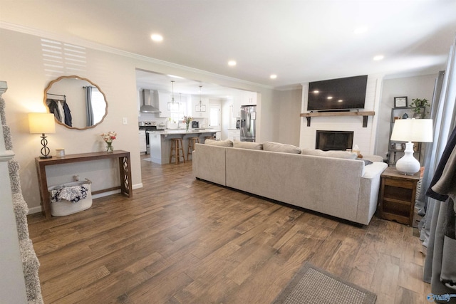 living room featuring wood finished floors, a fireplace, recessed lighting, and ornamental molding