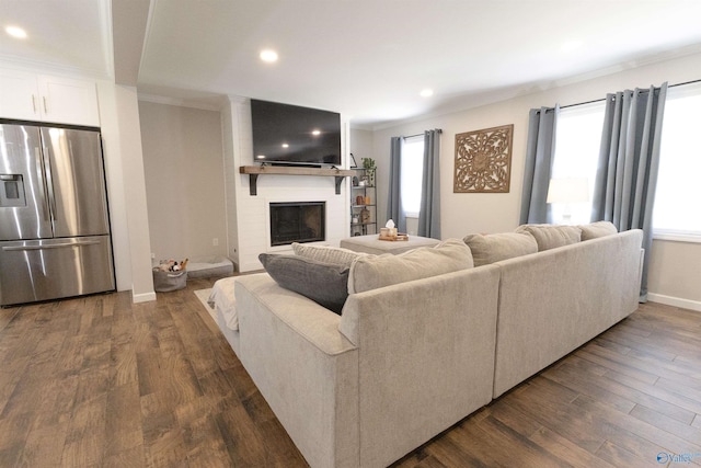living area with a fireplace, dark wood-type flooring, and ornamental molding