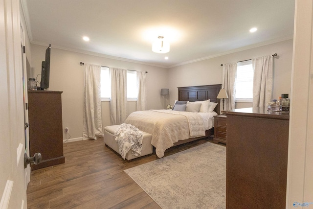 bedroom featuring recessed lighting, wood finished floors, ornamental molding, and multiple windows