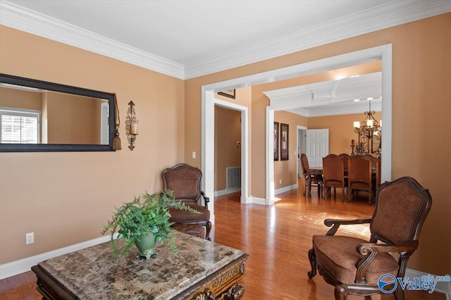 living area with wood finished floors, visible vents, ornamental molding, baseboards, and a chandelier