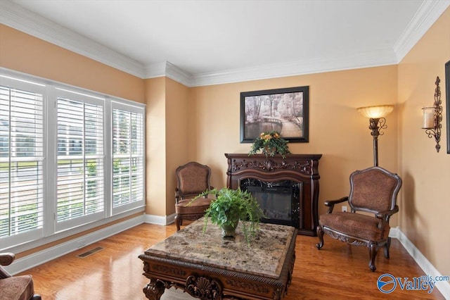 sitting room with baseboards, a glass covered fireplace, wood finished floors, and visible vents