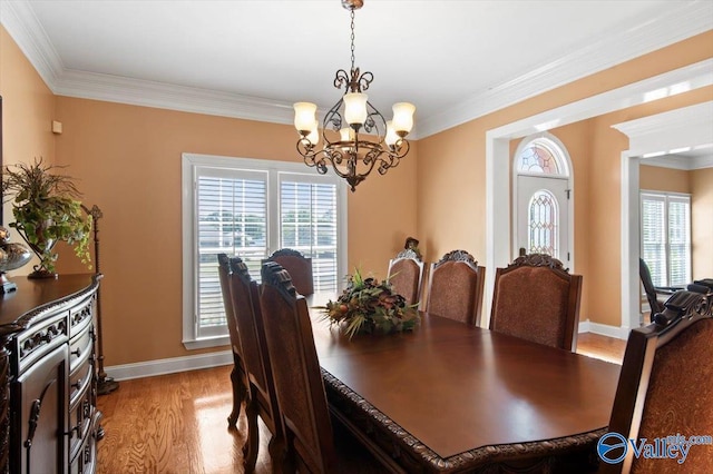 dining space with crown molding, a wealth of natural light, light wood finished floors, and a notable chandelier