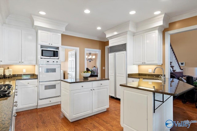 kitchen with paneled built in fridge, a center island, a sink, white double oven, and stainless steel microwave
