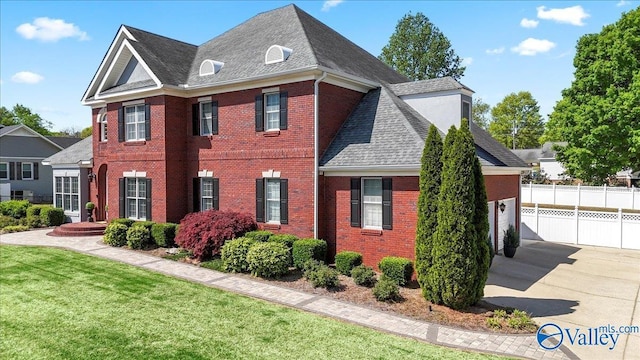 view of front of home featuring driveway, fence, a garage, brick siding, and roof with shingles