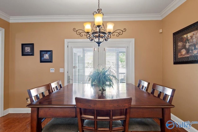 dining space with baseboards, crown molding, wood finished floors, and a chandelier