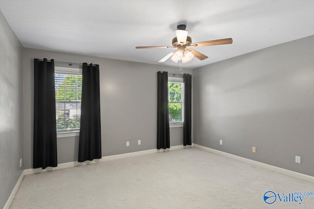 carpeted empty room with ceiling fan, a wealth of natural light, and baseboards