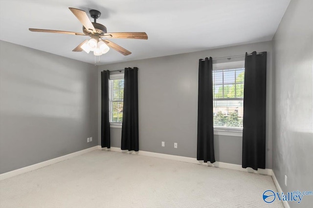 carpeted empty room featuring a wealth of natural light, baseboards, and ceiling fan