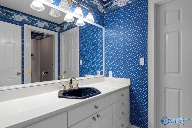 bathroom with wallpapered walls and vanity