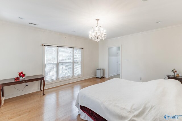 bedroom featuring light wood-type flooring, ornamental molding, and a chandelier