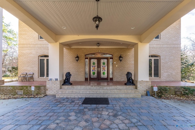 view of exterior entry with covered porch and french doors