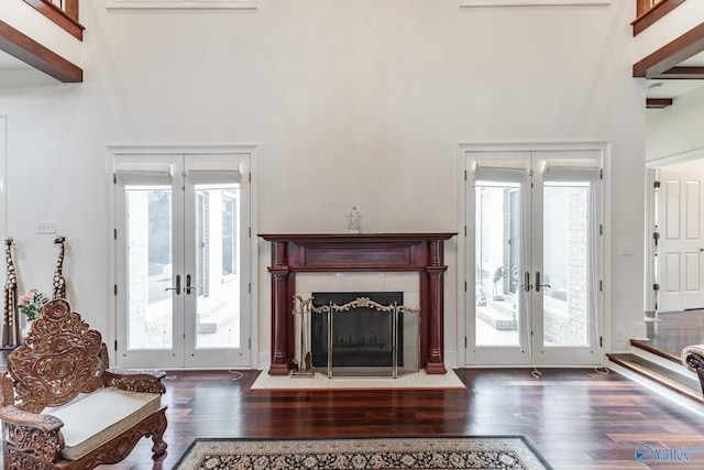 living room featuring dark wood-type flooring, a tile fireplace, and french doors