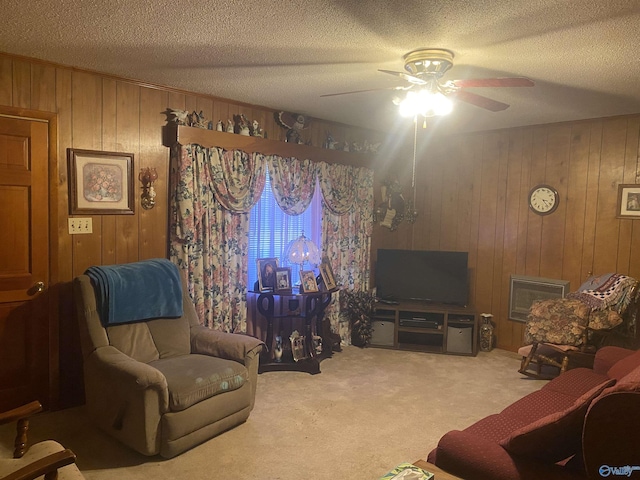 carpeted living room featuring ceiling fan, a textured ceiling, and wood walls