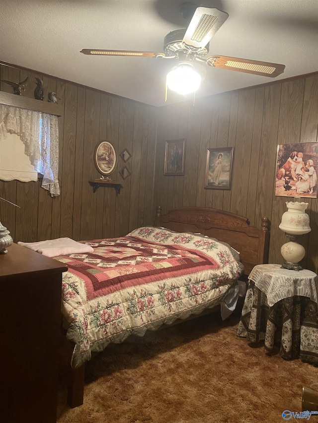 carpeted bedroom with ceiling fan and wood walls