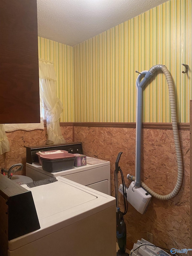 washroom with washing machine and clothes dryer and a textured ceiling
