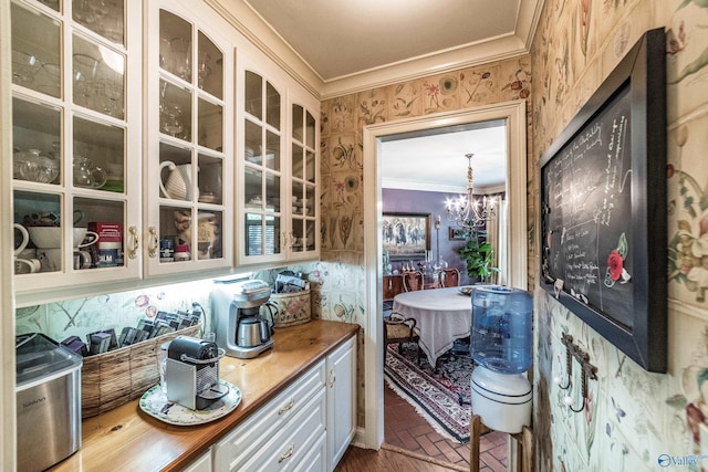 interior space with white cabinetry, a notable chandelier, crown molding, and pendant lighting